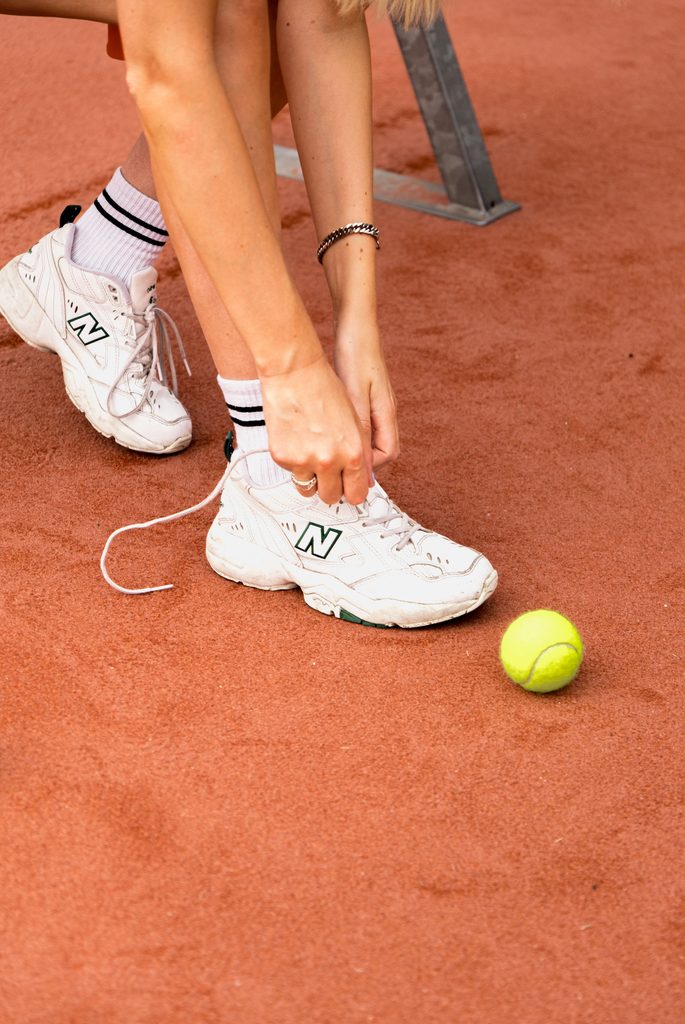 Chaussures : « Joueuse attachant ses chaussures de tennis avant une séance »